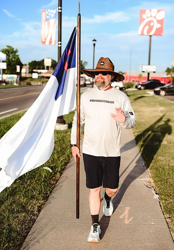 Founder of Coworkers Ministry, John Miller, walks the streets of Cabot with the Christian flag, waving to people he meets.